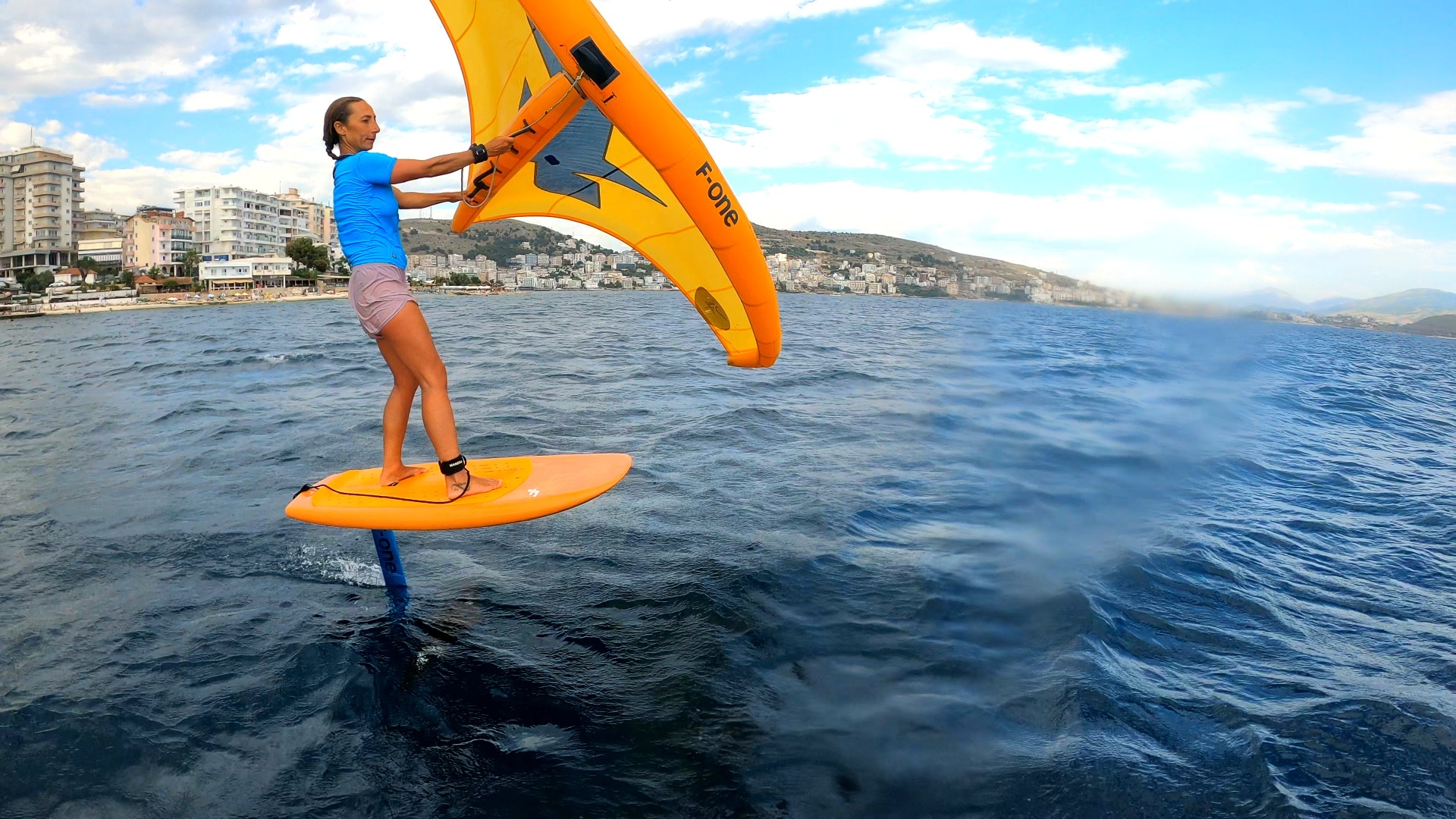 Wing foiler riding above the water near the Sarandë shoreline