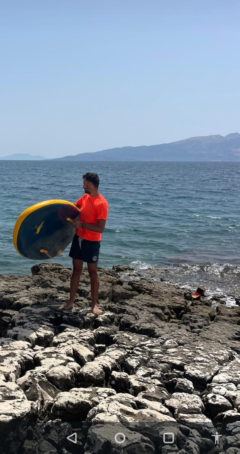 Instructor scouting the Ionian from the rocky Sarandë shoreline before a session