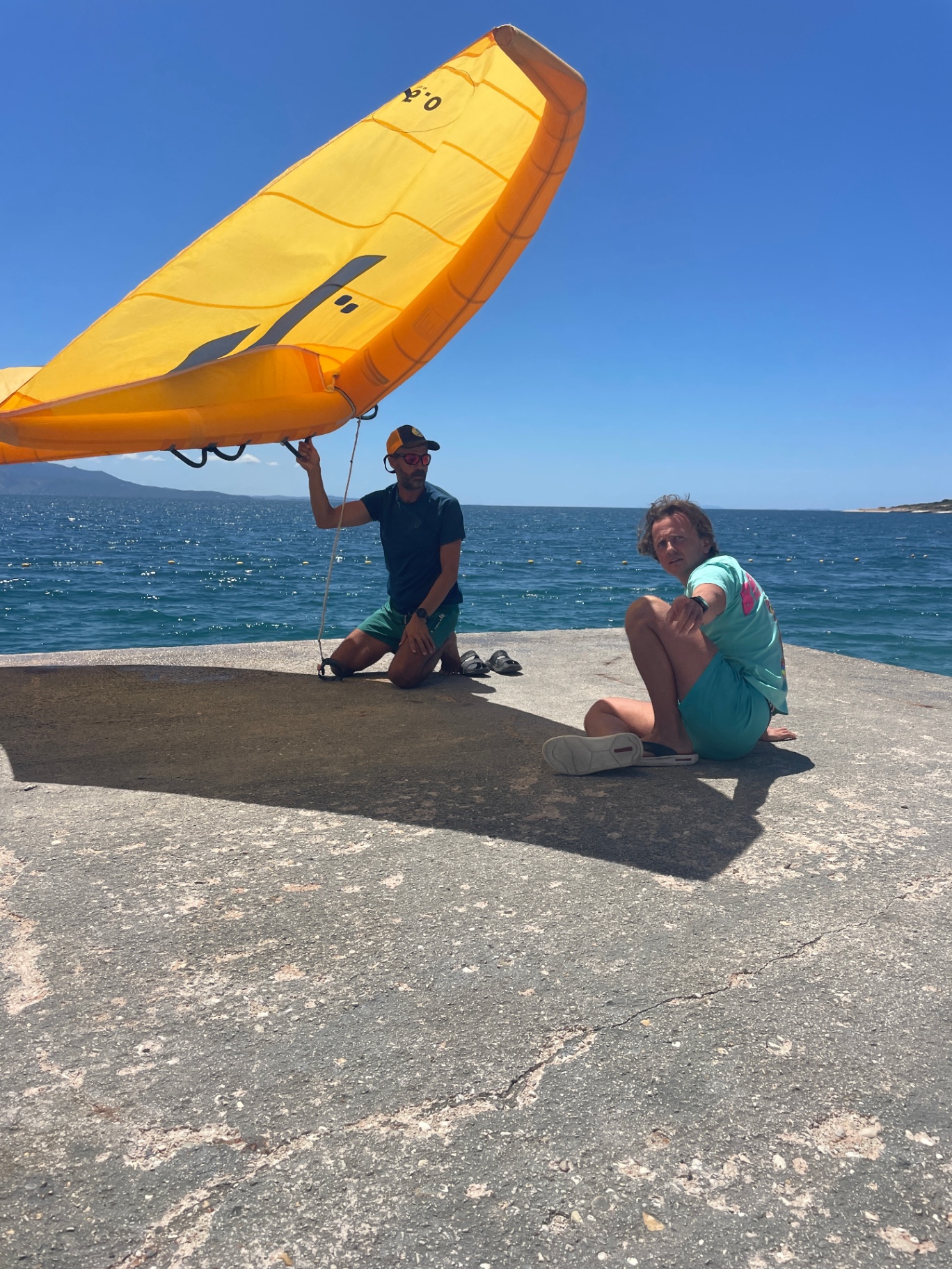 Wing foil coaching beneath a yellow wing on the Sarandë shoreline
