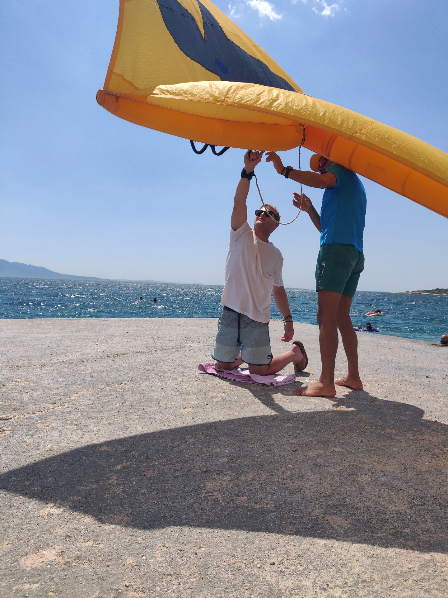 Rigging a yellow wing on the pier with the Ionian Sea behind