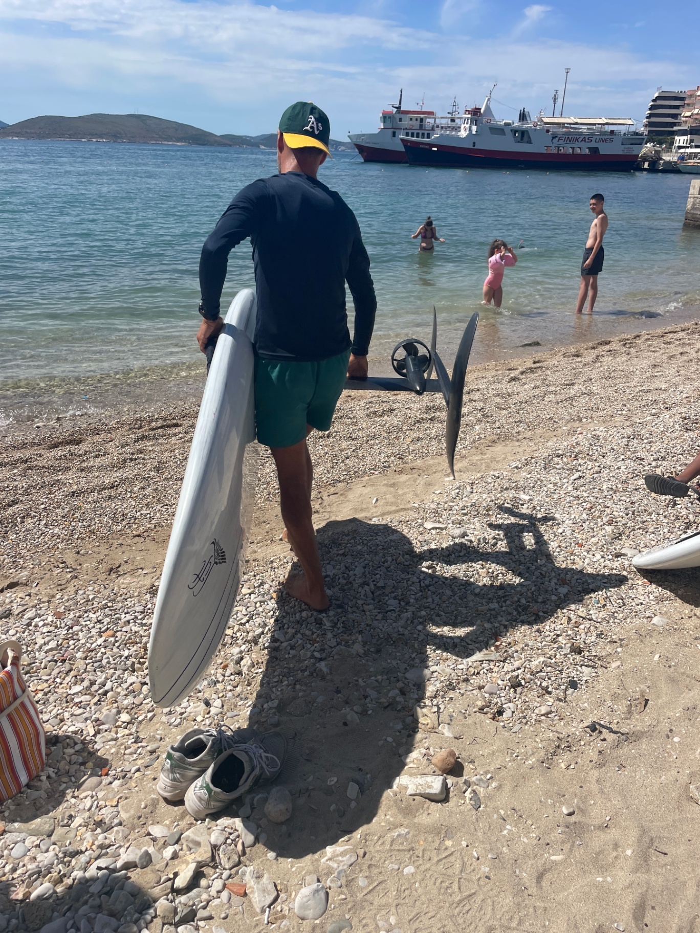Instructor carrying an eFoil board into the water in Sarandë bay